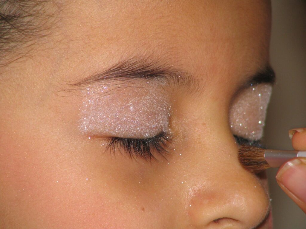 a woman with long eyelashes and a white eyeliners - File:Applying glitter to her eyelids.jpg